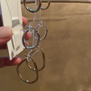 Set of 3 earring hoops. 2 are gold. 1 is silver.